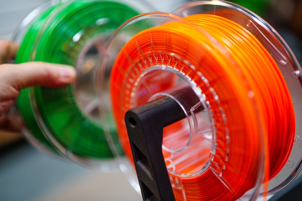 Mastering the First Impression: Your intriguing post title goes here Vibrant orange and green 3D printer filament spools for innovative manufacturing uses.